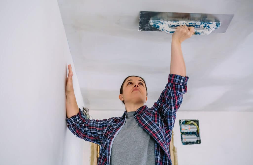 Bricklayer smoothing plaster ceiling with the trowel
