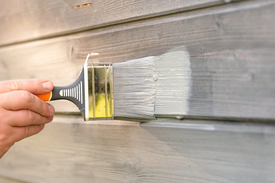 Woman Worker Painting Wooden House Exterior Wall With Paintbrush